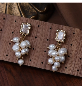 Detailed macro view of baroque pearl grape cluster earrings on a dark wood display