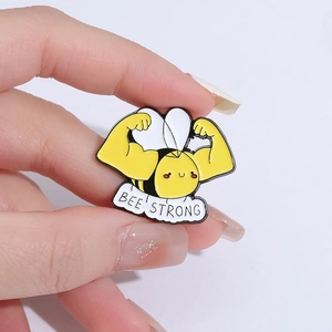 Cartoon bee enamel pin with strong muscular arms and Bee Strong motivational text