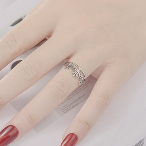 Detailed view of silver open ring with snowflake pattern worn on a model finger
