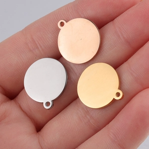 Three polished stainless steel round blank tags in gold, silver, and rose gold on a hand