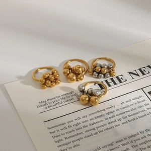Anelli con sfere lucide in oro e argento disposti su uno sfondo di giornale d'epoca