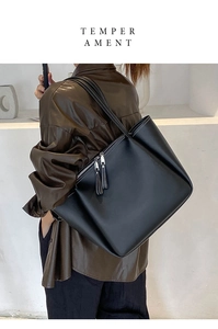 Detail view of large black tote bag featuring white contrast stitching and zip closure