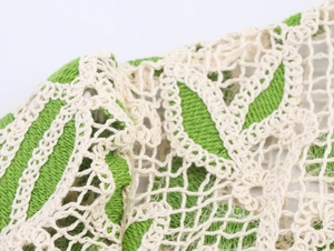 Détail macro du tricot ajouré vert et beige montrant la texture fine et le tissage