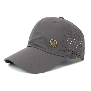 Detailed view of dark grey baseball cap featuring laser-cut ventilation and metal logo badge