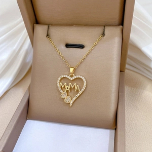 Close-up of golden heart pendant with MAMA letters and pavé zircons on silk background