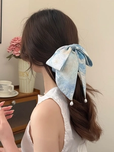Blue tie-dye bow hair clip with pearl pendant detail on a person's hairstyle