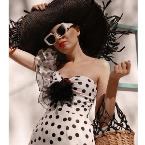 Close-up of retro polka dot ruffled swimsuit with swan feather detail and straw hat
