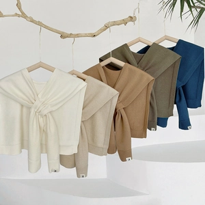 Fashionable knitted cape scarf shawl for women in multiple colors hanging on a rack