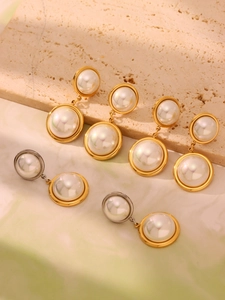 Close-up of pearl earrings with polished gold and silver metal frames on stone base