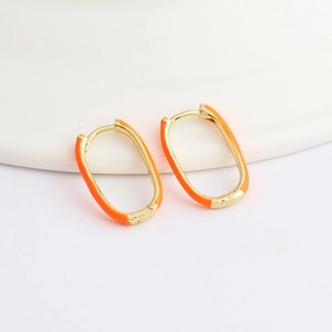 Macro detail of gold U-shaped oval hoop earrings with vibrant orange enamel coating