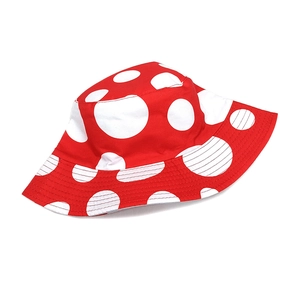 Detail shot of a reversible red bucket hat with white mushroom pattern and reinforced stitching