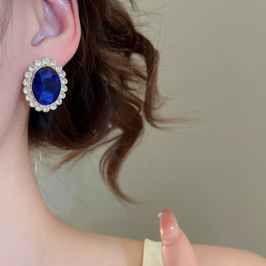 Close-up of vintage oval blue gemstone earring with white rhinestones and gold plating