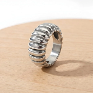 Macro shot of silver croissant ring on wood featuring polished ribbed texture