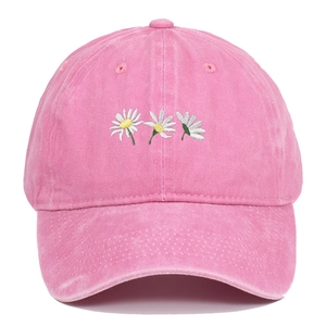 Dettaglio del cappellino rosa in cotone lavato con ricamo di margherite bianche