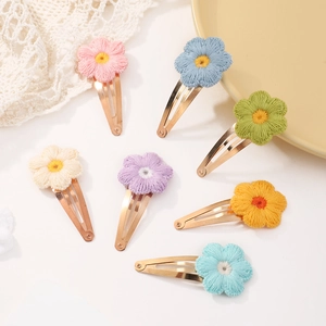 Detailed macro view of seven colorful embroidered sunflower hair clips with gold metal bases