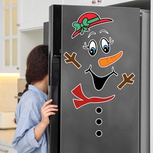 Magnetic snowman Christmas stickers applied to a gray refrigerator door in a kitchen setting