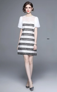 Detail of beaded neckline and puff sleeves on a white lace A-line dress with black trim