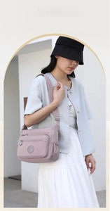 Pink waterproof nylon crossbody bag shown on model with multiple functional zip pockets