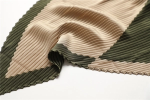 Detailed macro view of pleated silk scarf featuring beige and dark green color-blocking