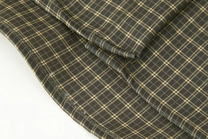 Detailed close-up of dark green and beige plaid woven fabric with fine stitching