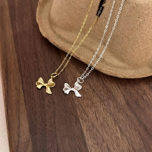 Elegant 925 sterling silver bow necklaces in gold and silver finish on wooden base
