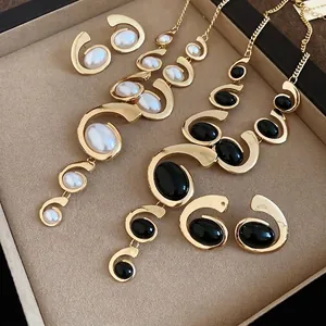 Elegant gold-plated metal jewelry set featuring oval pearl and black gemstone tassels