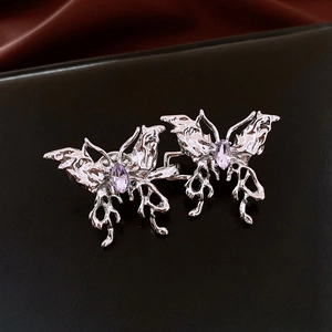 Détail de la boucle papillon argentée avec pierre violette sur surface réfléchissante