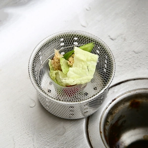 Close-up of a stainless steel mesh sink strainer filtering green vegetable residue effectively