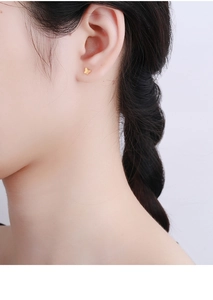 Detailed close-up of a minimalist gold butterfly stud earring on a female model's ear