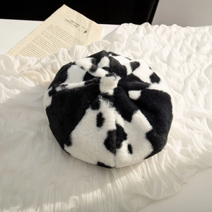 Detailed top view of soft cow print plush beret featuring black and white faux fur texture