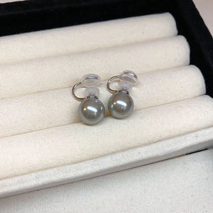 Detailed view of gray pearl clip-on earrings with gold accents in a jewelry box