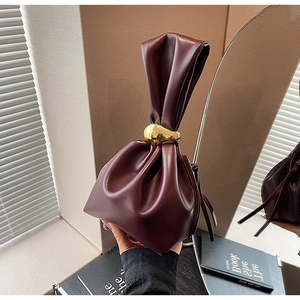 Close-up of wine red pleated bucket bag with decorative gold metal ring handle