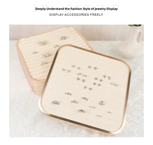 Detail of square beige velvet jewelry display trays with gold frames for rings and earrings