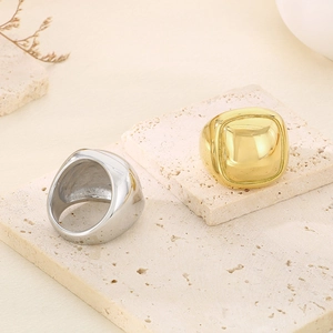 Polished chunky square rings in gold and silver finish on minimalist stone display