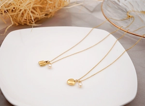 Détails des pendentifs cœur et cadenas dorés avec petites perles sur chaînes fines