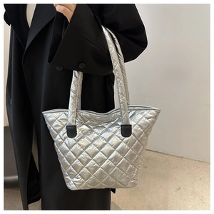 Macro detail of silver quilted tote bag with metallic finish and black leather trim