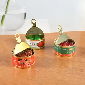 Miniature dollhouse food cans including beef, apple, and caviar designs on wood