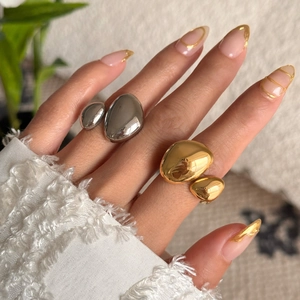 Macro detail of irregular 18k gold plated titanium steel pebble rings on soft knitwear
