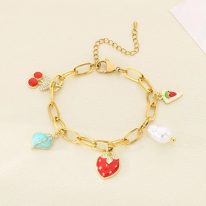 Detail of gold titanium steel bracelet with cherry, strawberry and pearl charms on cloth