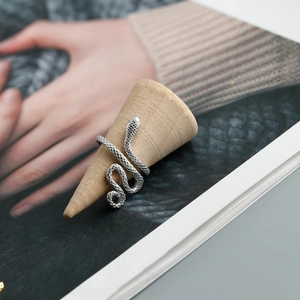 Macro detail of silver snake ring with textured scales on a wooden display cone