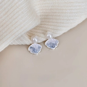 Close-up of silver shell earrings with white pearl and crystal fan pendant detail
