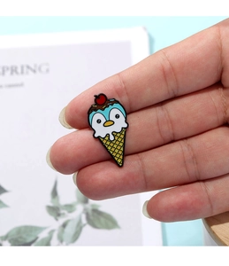 Macro shot of cute cartoon penguin ice cream enamel brooch with red cherry and waffle cone