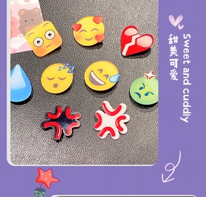 Dettaglio di fermagli per capelli in acrilico con vari emoji ed espressioni a cuore