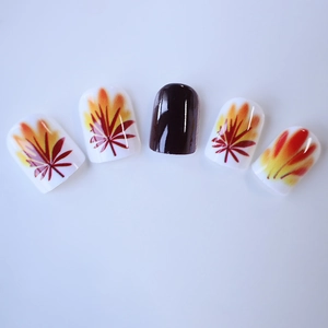 Short square press-on nails featuring autumn maple leaf designs and deep brown glossy finish