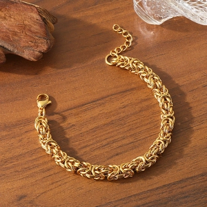 Detail of 18K gold-plated stainless steel woven bracelet with lobster clasp on wood
