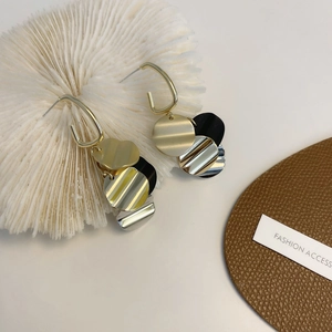 Detail of vintage long tassel earrings with gold, silver and black metal disks