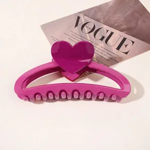 Detail of a large plum purple heart-shaped hair claw clip on a white surface
