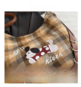Detail of plaid wool backpack featuring cartoon dog print and leather strap with metal ring