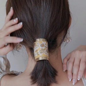 Golden metal ponytail hook with yellow floral embroidery fabric on a low ponytail