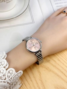Close-up of a women's watch with pink dial and silver metallic chain strap on wrist